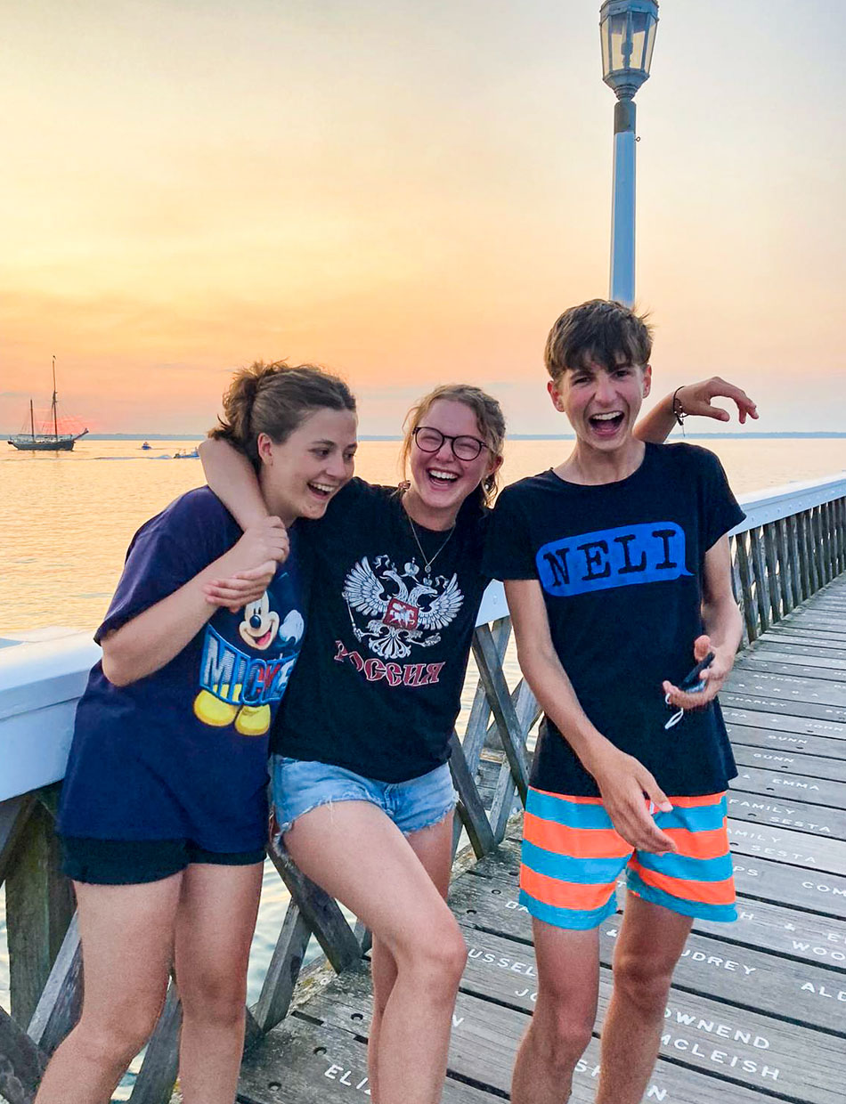 Teenage friends on Yarmouth pier at sunset, laughing happily